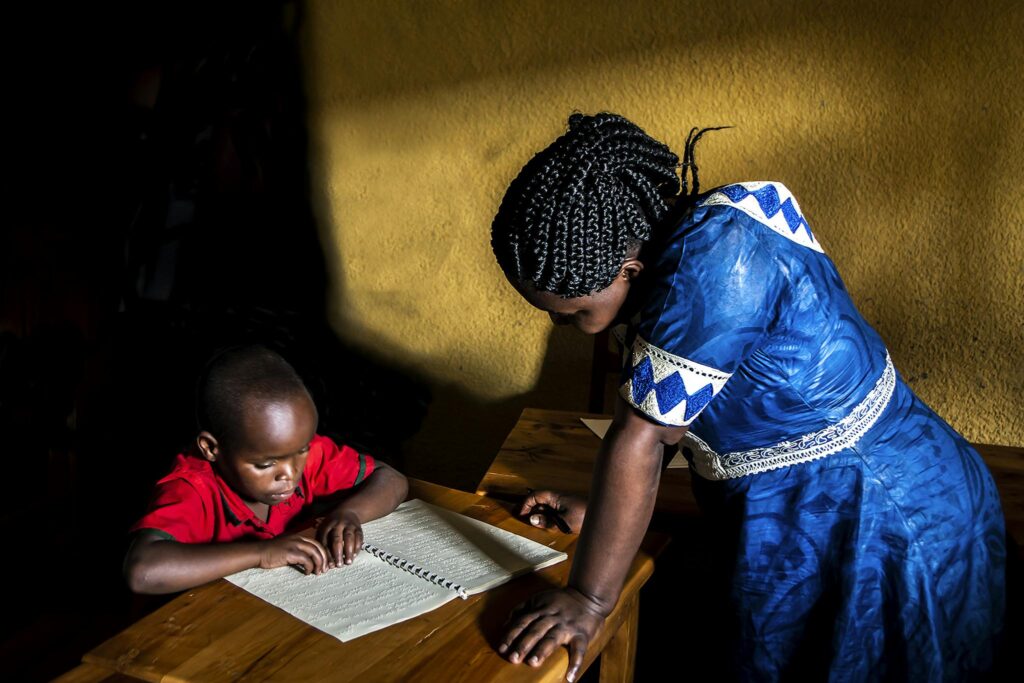 African student and teacher engage in braille reading. Northern Province, Rwanda.
